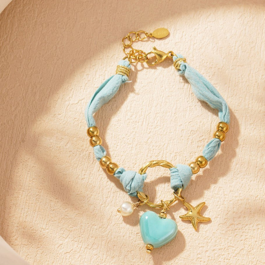Pulsera de tela y acero, dijes corazón grande, estrella marina, perla acabado verde agua y dorado - mbyou