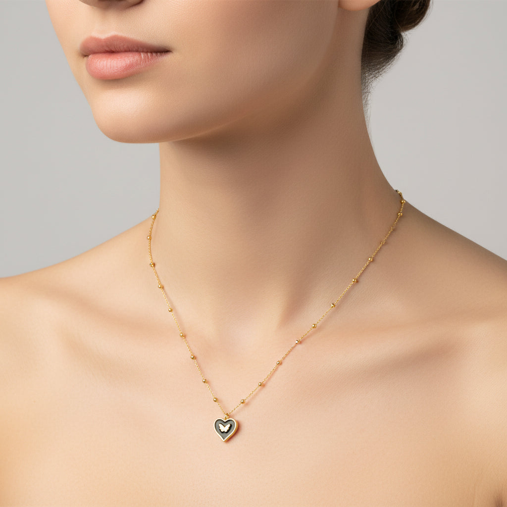 Collar de acero con dije de corazón negro con mariposa acabado oro