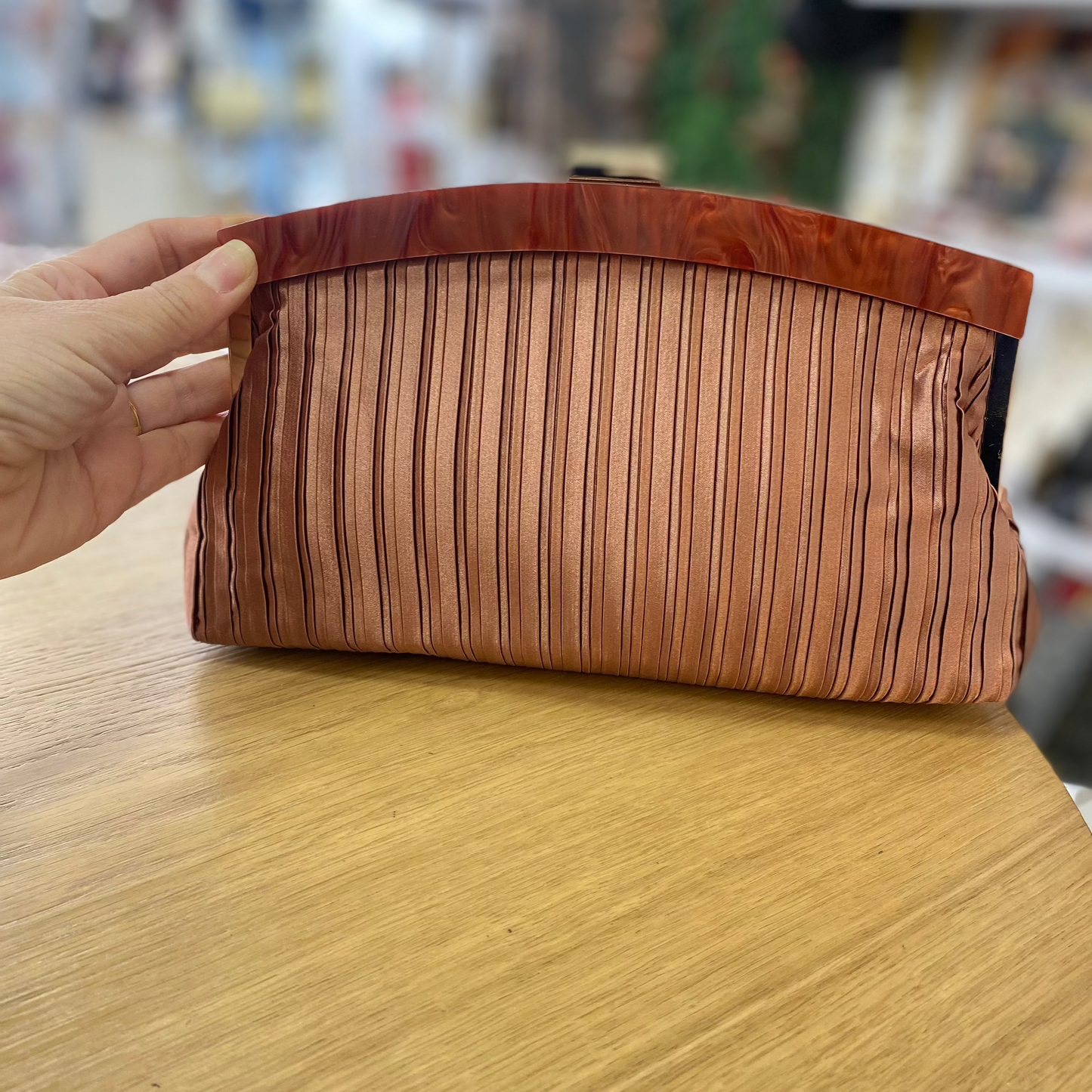 Bolso fiesta clutch asalmonado con textura plisada y mango marmolado