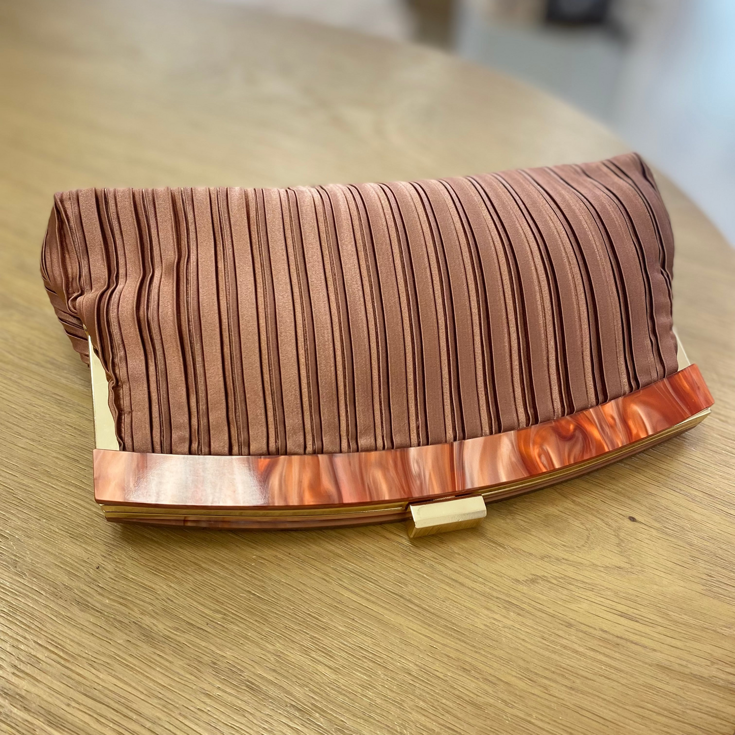 Bolso fiesta clutch asalmonado con textura plisada y mango marmolado
