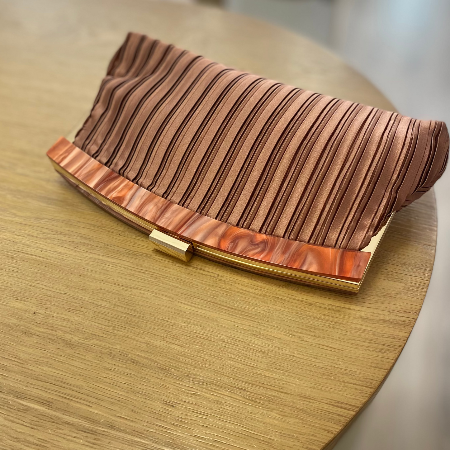 Bolso fiesta clutch asalmonado con textura plisada y mango marmolado