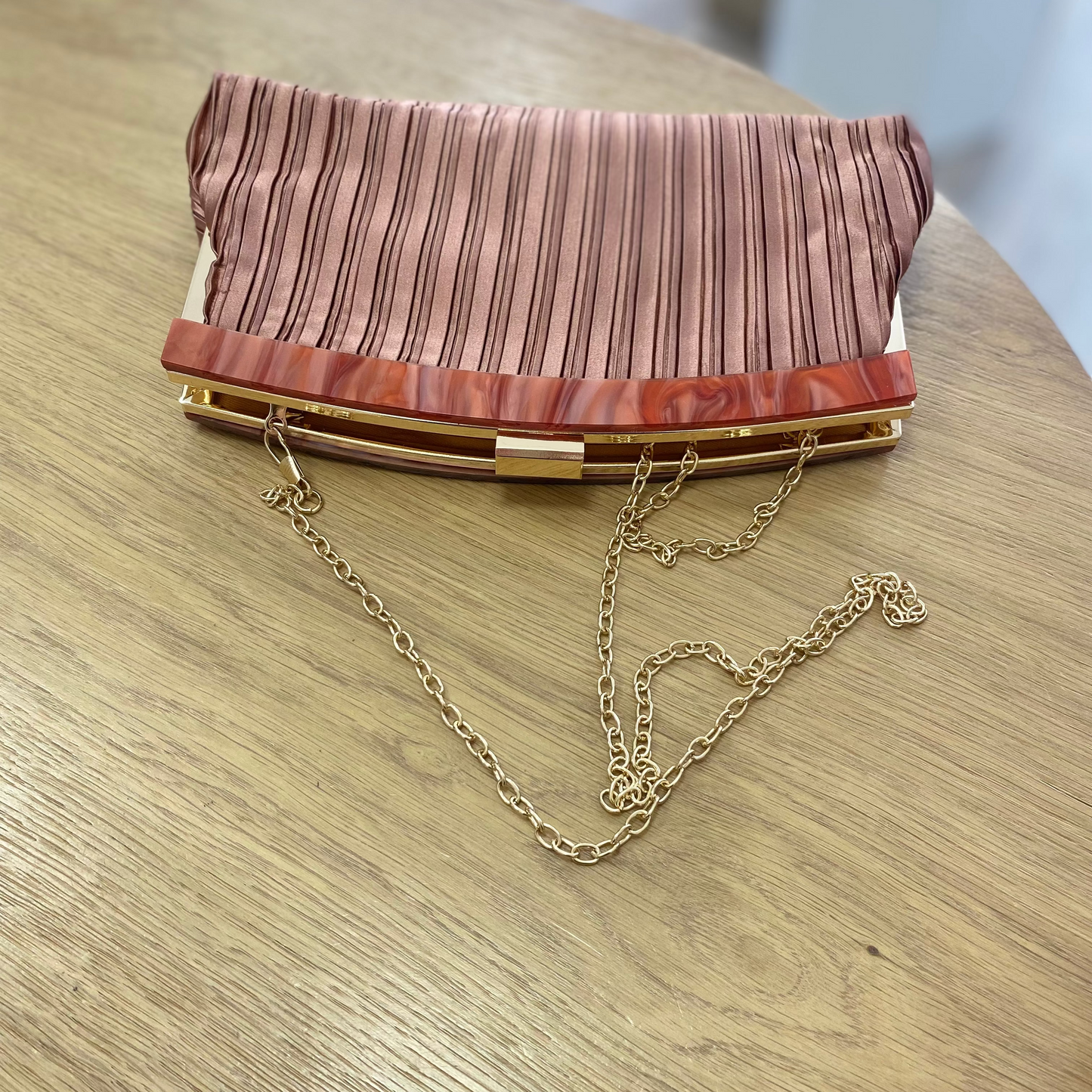 Bolso fiesta clutch asalmonado con textura plisada y mango marmolado