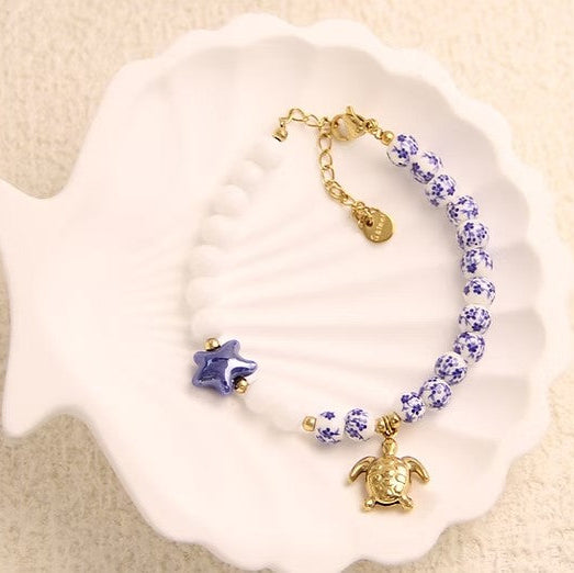 Pulsera de acero con cuentas de porcelana de estampado floral y lisas y con dije de tortuga - Moments by You
