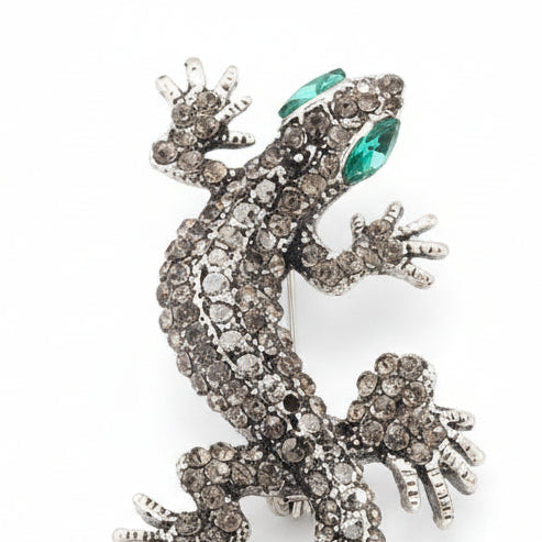 Broche en forma de lagartija en color gris, ojos verdes y acabado plata