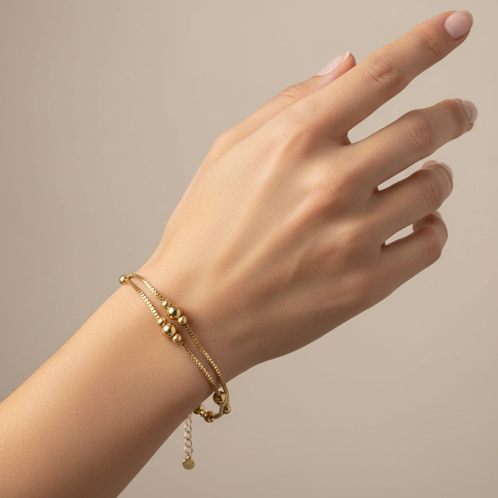 Pulsera acero con doble cadena con esferas pequeñas en diferentes texturas en acabado oro